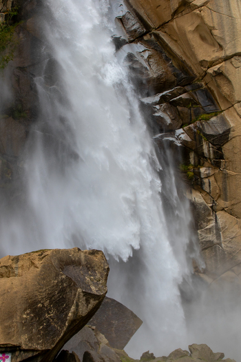 View of Khamosh Waterfall cascading down rugged rocky cliffs with mist and spray in Skardu Gilgit Pakistan.
