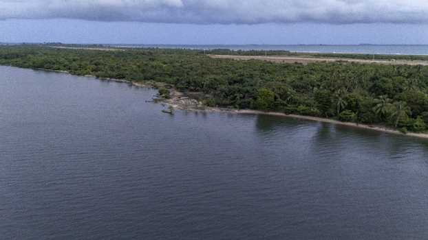 Aerial view of the lush green coastline and dense tropical forest along the calm water under a cloudy sky in Badagry Lagos Nigeria. Aerial view of the lush green coastline and dense tropical forest along the calm water under a cloudy sky in Badagry Lagos Nigeria.