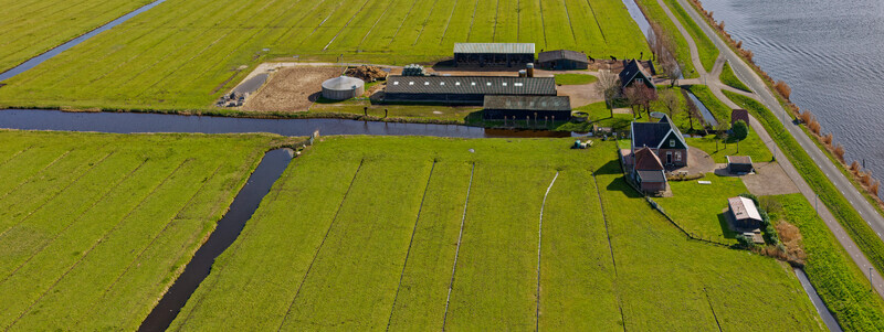 Aerial view of lush green fields divided by dark canals interspersed with traditional farmhouses creating a vibrant patchwork of nature and agriculture Wormer Netherlands. Aerial view of lush green fields divided by dark canals interspersed with traditional farmhouses creating a vibrant patchwork of nature and agriculture Wormer Netherlands.
