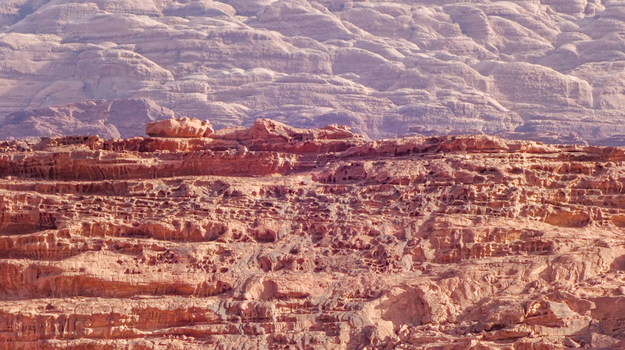 View of the rugged sandstone rock formations of the Wadi Rum Desert featuring weathered textures and layered cliffs under bright daylight in Wadi Rum Village Aqaba Governorate Jordan. View of the rugged sandstone rock formations of the Wadi Rum Desert featuring weathered textures and layered cliffs under bright daylight in Wadi Rum Village Aqaba Governorate Jordan.