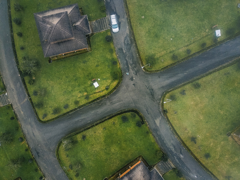 Aerial view of dark roofed buildings nestled amidst vibrant green lawns and winding wet asphalt roads Obudu Cross River Nigeria.