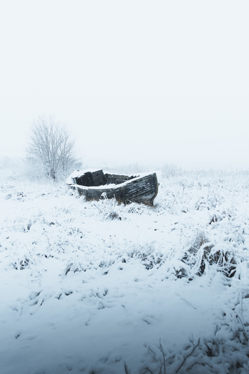 View of an old wooden boat abandoned in a snow covered field during winter in Toolse Laane Viru County Estonia. View of an old wooden boat abandoned in a snow covered field during winter in Toolse Laane Viru County Estonia.
