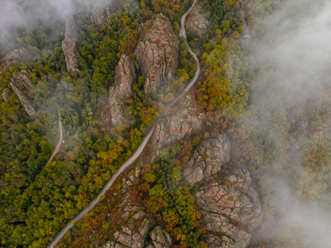 Aerial view of Belogradchik Rocks surrounded by autumn forest and a winding road partially obscured by mist in Belogradchik Vidin Bulgaria. Aerial view of Belogradchik Rocks surrounded by autumn forest and a winding road partially obscured by mist in Belogradchik Vidin Bulgaria.