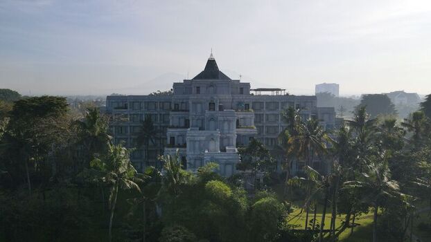 Aerial view of Hyatt Regency Yogyakarta surrounded by lush tropical palm trees and greenery under a soft morning sky in Kecamatan Ngaglik Daerah Istimewa Yogya Indonesia. Aerial view of Hyatt Regency Yogyakarta surrounded by lush tropical palm trees and greenery under a soft morning sky in Kecamatan Ngaglik Daerah Istimewa Yogya Indonesia.