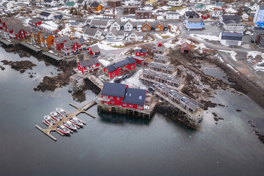 Aerial view of striking red buildings contrast against the muted greys of the surrounding landscape and the cold still waters Ballstad Nordland Norway. Aerial view of striking red buildings contrast against the muted greys of the surrounding landscape and the cold still waters Ballstad Nordland Norway.