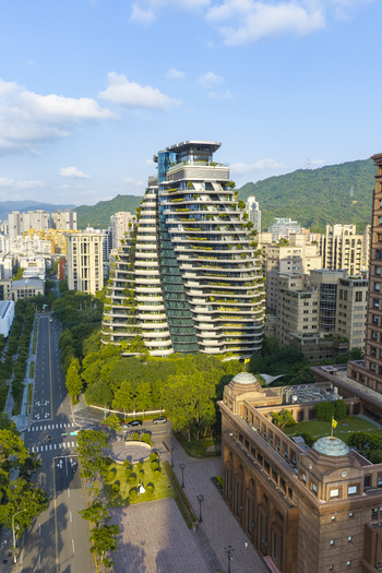 Aerial view of the Tao Zhu Yin Yuan skyscraper with its distinctive twisting design and lush vertical gardens surrounded by urban buildings and mountains in Taipei Taiwan. Aerial view of the Tao Zhu Yin Yuan skyscraper with its distinctive twisting design and lush vertical gardens surrounded by urban buildings and mountains in Taipei Taiwan.