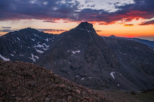 Aerial view of Mount of the Holy Cross in the Sawatch Range at sunrise with rugged rocky slopes lingering snow patches and a vibrant colorful sky in Vail Colorado United States. Aerial view of Mount of the Holy Cross in the Sawatch Range at sunrise with rugged rocky slopes lingering snow patches and a vibrant colorful sky in Vail Colorado United States.
