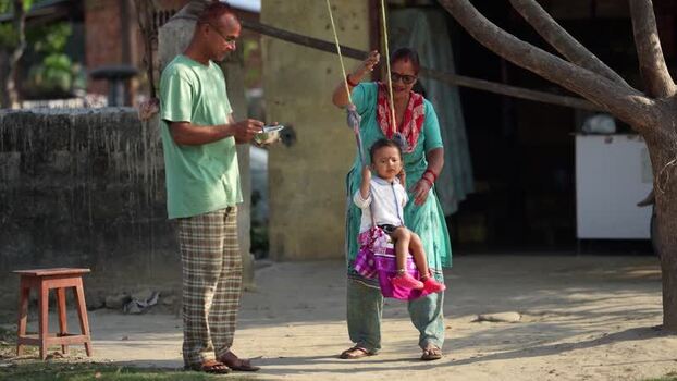 View of a family playing with a child on a swing Nepal. View of a family playing with a child on a swing Nepal.