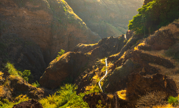 Aerial view of the rugged canyon landscape of Santo Antao with steep rocky slopes golden dry grass and a winding path in Alto Mira Porto Novo Cabo Verde.