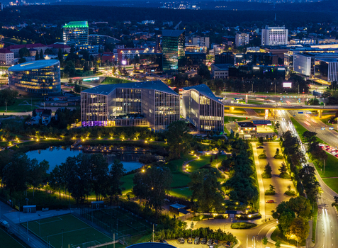 Aerial view of the illuminated modern business district featuring contemporary skyscrapers a park with a pond and glowing traffic light trails at night in Vilnius Vilnius County Lithuania. Aerial view of the illuminated modern business district featuring contemporary skyscrapers a park with a pond and glowing traffic light trails at night in Vilnius Vilnius County Lithuania.