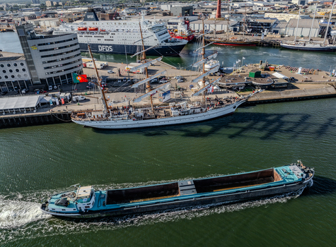 IJmuiden Netherlands 19 August 2025 Aerial view of the harbor featuring a large white tall ship docked at the pier a DFDS ferry in the background NRP Sagres and a cargo barge cruising through the water. IJmuiden Netherlands 19 August 2025 Aerial view of the harbor featuring a large white tall ship docked at the pier a DFDS ferry in the background NRP Sagres and a cargo barge cruising through the water.