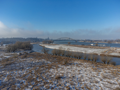 Aerial view of the snow dusted landscape with a bridge spanning the tranquil river under a clear sky Tiengeboden Gelderland Netherlands. Aerial view of the snow dusted landscape with a bridge spanning the tranquil river under a clear sky Tiengeboden Gelderland Netherlands.