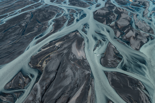 Aerial view of a braided river system with glacial water flowing through dark volcanic sand in Skaftarhreppur Iceland.