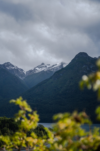 View of Parque Nacional Los Alerces with snow capped mountains dense forest and a lake under a cloudy sky in Futaleufu Department Chubut Province Argentina. View of Parque Nacional Los Alerces with snow capped mountains dense forest and a lake under a cloudy sky in Futaleufu Department Chubut Province Argentina.