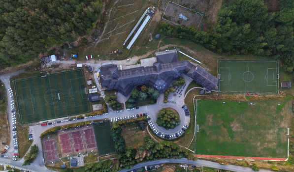Aerial view of Brzece Sports Center featuring multiple soccer fields tennis courts and a large hotel complex surrounded by lush forest in Brzece Rasina District Serbia.
