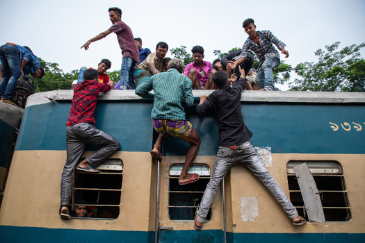 Dhaka Bangladesh 14 June 2018 View of people climbing onto the roof of a crowded train at Airport Railway Station during the Eid al Fitr holiday rush. Dhaka Bangladesh 14 June 2018 View of people climbing onto the roof of a crowded train at Airport Railway Station during the Eid al Fitr holiday rush.