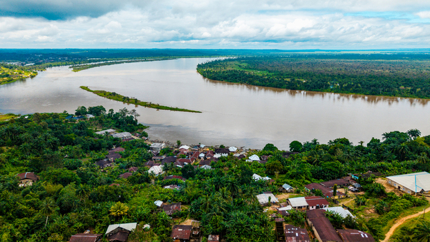 Aerial view of the town of Itu featuring residential buildings nestled among dense tropical vegetation along the banks of the Cross River in Itu Akwa Ibom Nigeria. Aerial view of the town of Itu featuring residential buildings nestled among dense tropical vegetation along the banks of the Cross River in Itu Akwa Ibom Nigeria.