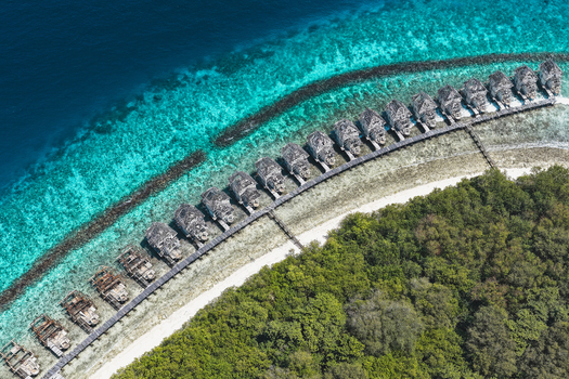 Aerial view of an abandoned island resort with lush green vegetation white sandy beaches and turquoise coral reefs surrounded by deep blue ocean waters in Muraidhoo Haa Alif Atoll Maldives. Aerial view of an abandoned island resort with lush green vegetation white sandy beaches and turquoise coral reefs surrounded by deep blue ocean waters in Muraidhoo Haa Alif Atoll Maldives.