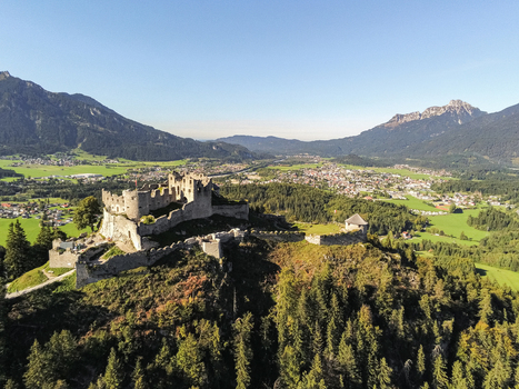Aerial view of Burg Hohenwerfen perched on a rocky hill surrounded by lush green valleys dense forests and the majestic Alps under a clear blue sky in Werfen Salzburg Austria. Aerial view of Burg Hohenwerfen perched on a rocky hill surrounded by lush green valleys dense forests and the majestic Alps under a clear blue sky in Werfen Salzburg Austria.