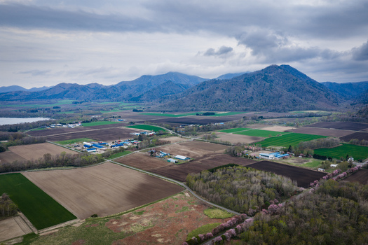 Aerial view of Lake Kussharo surrounded by agricultural fields rural farms and mountains under a cloudy sky in Teshikaga Hokkaido Japan. Aerial view of Lake Kussharo surrounded by agricultural fields rural farms and mountains under a cloudy sky in Teshikaga Hokkaido Japan.