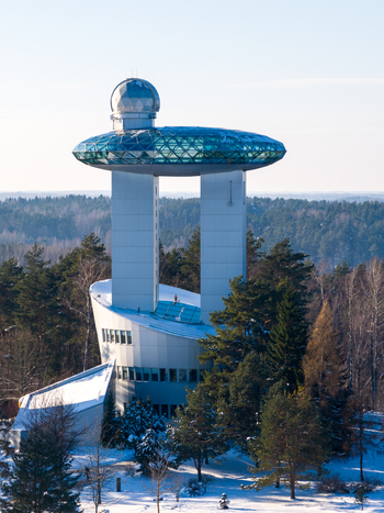 Aerial view of the Lithuanian Museum of Ethnocosmology featuring futuristic architecture with glass observation decks above a snowy pine forest Kulionys Utenos apskritis Lithuania.