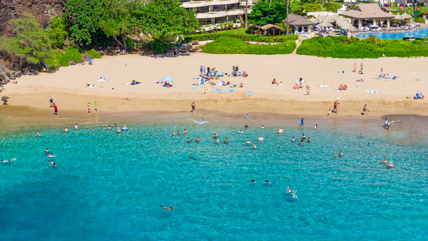 Aerial view of turquoise water gently kissing the golden sands where people relax framed by verdant hills and luxurious resorts Lahaina Hawaii United States. Aerial view of turquoise water gently kissing the golden sands where people relax framed by verdant hills and luxurious resorts Lahaina Hawaii United States.