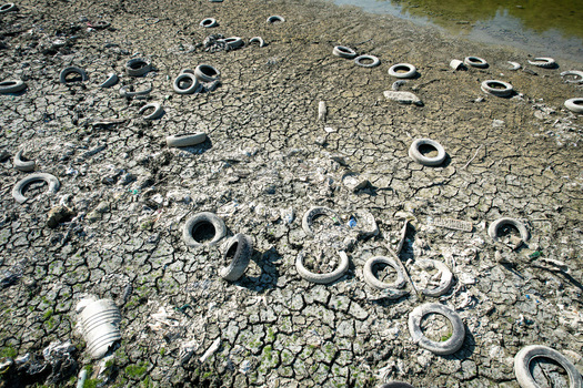 Aerial view of discarded tires and waste scattered across cracked dry earth during a severe drought in Carignano Piemonte Italy. Aerial view of discarded tires and waste scattered across cracked dry earth during a severe drought in Carignano Piemonte Italy.