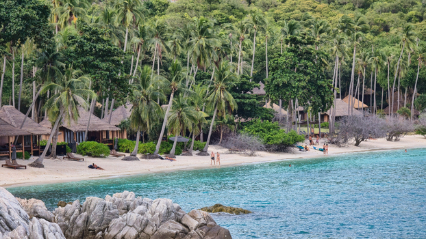 Ko Tao Surat Thani Thailand 28 September 2025 View of Ko Tao beach with tropical palm trees wooden bungalows turquoise water and rocky foreground.