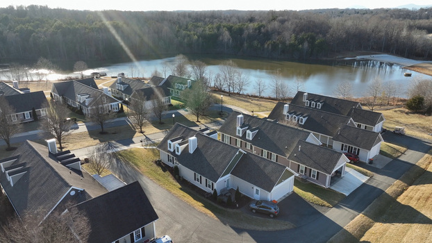Aerial view of residential houses with dark roofs situated near a calm lake surrounded by trees in Lynchburg Virginia United States. Aerial view of residential houses with dark roofs situated near a calm lake surrounded by trees in Lynchburg Virginia United States.