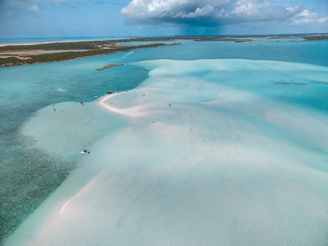 Aerial view of Man O War Cay Sandbar with small boats and people on the white sand surrounded by turquoise water in Rolletown Exuma The Bahamas. Aerial view of Man O War Cay Sandbar with small boats and people on the white sand surrounded by turquoise water in Rolletown Exuma The Bahamas.