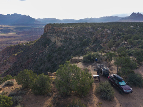 Aerial view of an overland teardrop camper trailer parked on the edge of Gooseberry Mesa with a view of the rugged canyons of Zion National Park in Hurricane Utah United States.