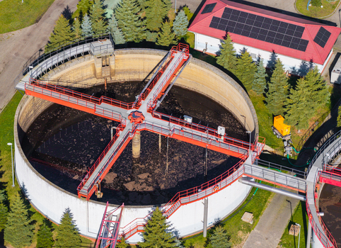 Aerial view of a wastewater treatment plant with circular sedimentation tanks metal walkways and surrounding pine trees in Pomeranian Voivodeship Poland. Aerial view of a wastewater treatment plant with circular sedimentation tanks metal walkways and surrounding pine trees in Pomeranian Voivodeship Poland.