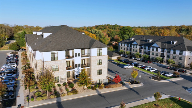 Aerial view of a modern apartment complex with stone and white siding surrounded by parking lots and autumn trees in Lynchburg Virginia United States. Aerial view of a modern apartment complex with stone and white siding surrounded by parking lots and autumn trees in Lynchburg Virginia United States.