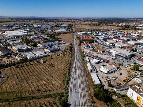 Aerial view of a railway line cutting through an industrial zone with warehouses and surrounding agricultural fields in Evora Evora District Portugal. Aerial view of a railway line cutting through an industrial zone with warehouses and surrounding agricultural fields in Evora Evora District Portugal.