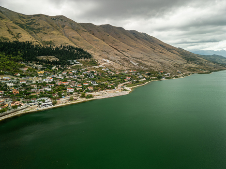 Aerial view of the village of Shiroka nestled between the green waters of Lake Shkodra and the rugged mountains in Shiroka Shkoder County Albania.