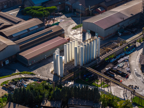 Aerial view of Acciai Speciali Terni S.p.A. featuring large white cylindrical storage tanks industrial factory buildings and surrounding infrastructure in Terni Umbria Italy.