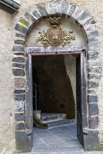 View of the ornate stone archway and coat of arms at the entrance of Eltz Castle with stone steps leading into the historic fortress in Wierschem Rhineland Palatinate Germany.