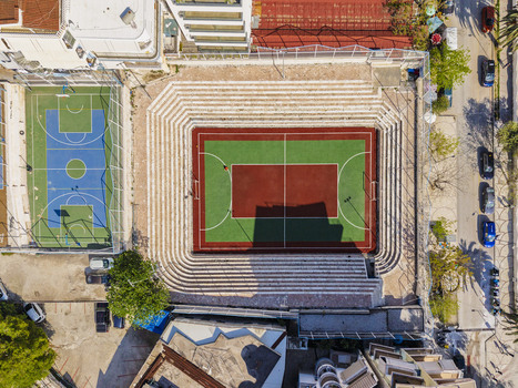 Aerial view of a multi purpose sports court with a red and green surface surrounded by tiered concrete seating adjacent to a blue basketball court in Saranda Vlore County Albania. Aerial view of a multi purpose sports court with a red and green surface surrounded by tiered concrete seating adjacent to a blue basketball court in Saranda Vlore County Albania.