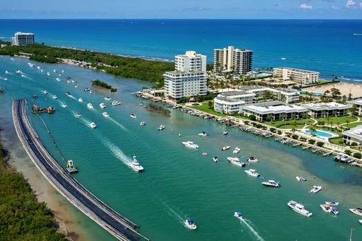 Aerial view of boats cruising through the turquoise waters of the Intracoastal Waterway past waterfront condominiums and lush tropical greenery Jupiter Florida United States. Aerial view of boats cruising through the turquoise waters of the Intracoastal Waterway past waterfront condominiums and lush tropical greenery Jupiter Florida United States.