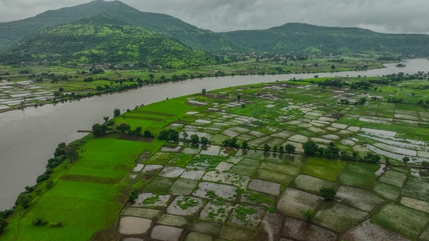 Aerial view of lush green paddy fields and a winding river flowing through the landscape near the Mumbai Goa Highway in Mahad Maharashtra India.