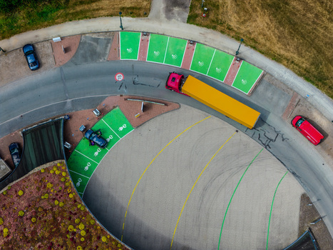 Aerial view of electric vehicle charging stations with green painted parking spots a yellow truck and parked cars in a modern parking lot in Beilen Drenthe Netherlands.