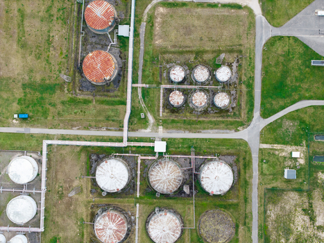 Aerial view of industrial oil storage tanks with rusted and white circular containers connected by pipes in a grassy field in Olaine parish Olaine Municipality Latvia.