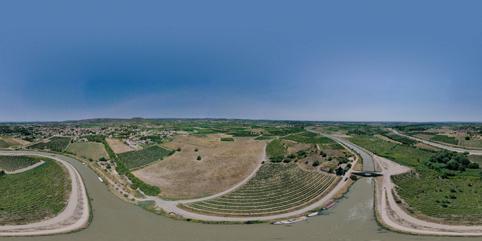 Aerial view of the Canal du Midi winding through lush vineyards near Le Chat Qui Peche in the rural landscape of Argeliers Occitanie France.