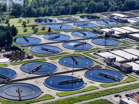 Aerial view of the Impianto depurazione water treatment plant with circular sedimentation tanks surrounded by green lawns and trees Castiglione Torinese Piedmont Italy.