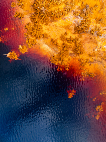 Aerial view of a tailing pond with its vibrant red and orange mineral deposits contrasting against the dark blue water in Andalusia Spain. Aerial view of a tailing pond with its vibrant red and orange mineral deposits contrasting against the dark blue water in Andalusia Spain.