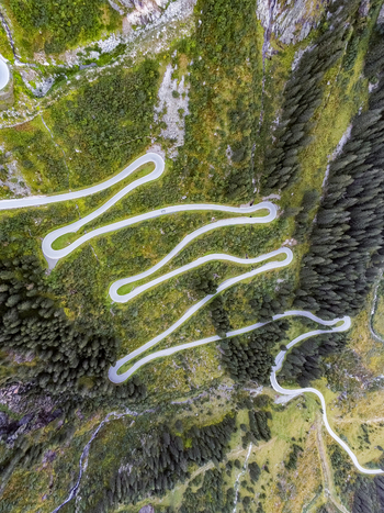 Aerial view of the winding switchbacks of the Silvretta Hochalpenstrasse mountain road surrounded by lush green alpine forests and steep mountain slopes in Partenen Vorarlberg Austria. Aerial view of the winding switchbacks of the Silvretta Hochalpenstrasse mountain road surrounded by lush green alpine forests and steep mountain slopes in Partenen Vorarlberg Austria.