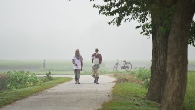 View of two men walking on a misty rural road Bangladesh.