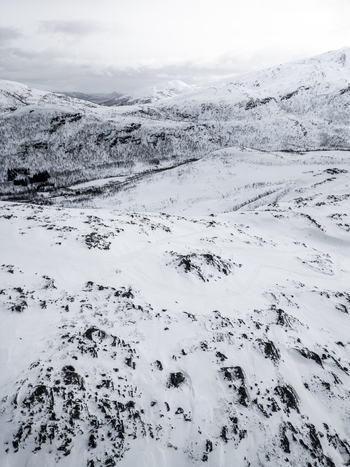 Aerial view of snow covered mountain peaks and rocky slopes under an overcast sky Ersfjord Troms Norway. Aerial view of snow covered mountain peaks and rocky slopes under an overcast sky Ersfjord Troms Norway.
