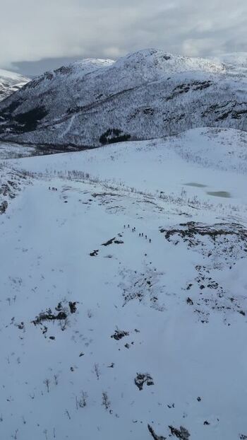 Aerial view of people hiking on the snowy slopes of Kvaloya Norway.