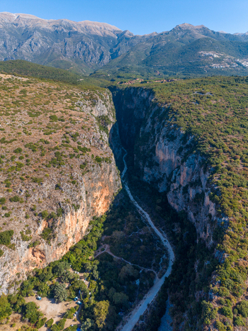 Aerial view of Gjipe Canyon with its steep limestone cliffs lush green vegetation and a winding path leading towards the coast Vlore County Albania. Aerial view of Gjipe Canyon with its steep limestone cliffs lush green vegetation and a winding path leading towards the coast Vlore County Albania.
